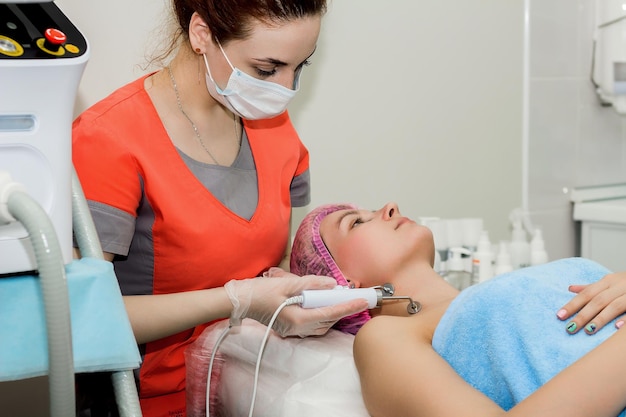 Uma bela mulher faz um procedimento cosmético para melhorar a condição da pele facial com microcorrentes