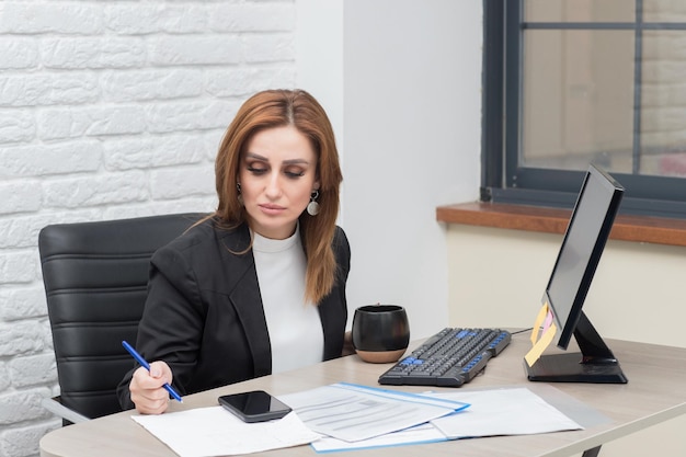 Uma bela senhora sentada à mesa tomando notas