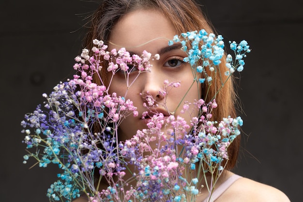 Uma bela senhora sexy em uma elegante roupa nua segura flores nas mãos Retrato de beleza da moda da garota modelo de moda no estúdio