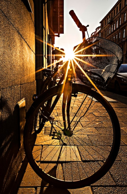 Uma bicicleta está estacionada em uma calçada com o sol brilhando sobre ela.