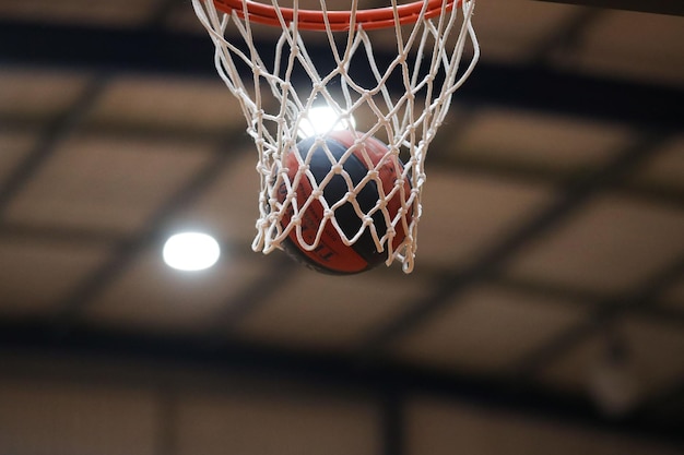 Uma bola de basquete cai em uma rede de basquete durante um jogo de basquete em um estádio coberto