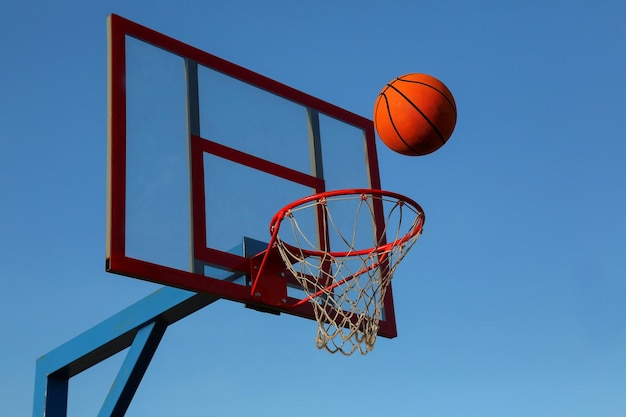 Uma bola de basquete contra o céu azul está voando para a cesta