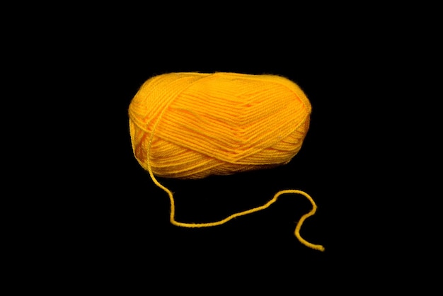 Uma bola de fio amarelo sobre um fundo preto. Bola de lã dourada, vintage