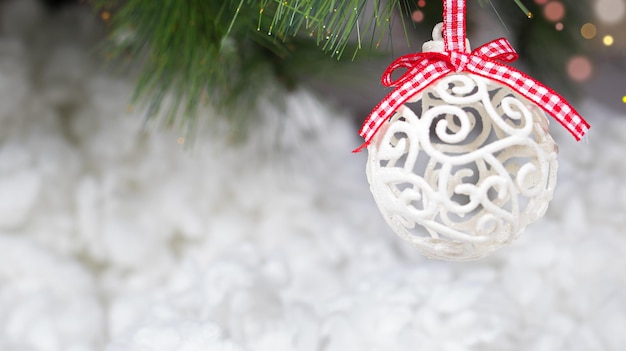 Uma bola de natal branca e um galho de árvore coberto de neve em um fundo branco nevado banner de cartão horizontal para texto