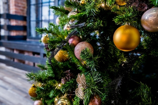 Uma bola dourada brilhante em um galhoDecorações da árvore de Natal Decorações de ano novo em tons de rosa e dourado Parabéns pelas férias de inverno Preparação para a celebração Cartão postal