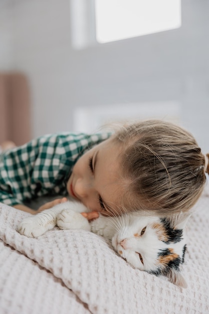 uma bonita menina de seis anos adormeceu doce ao lado de um gato fofo em sua cama criança com gato dormir na cama branca