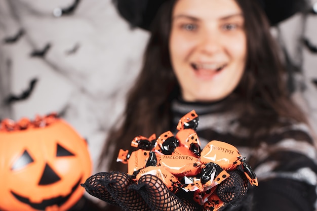 Uma bruxa segurando doces de laranja no Halloween e rindo