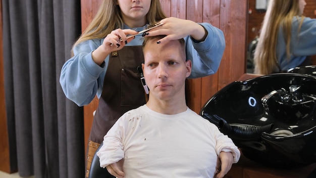 Uma cabeleireira em um salão de beleza faz um corte de cabelo e penteado para um homem com deficiência