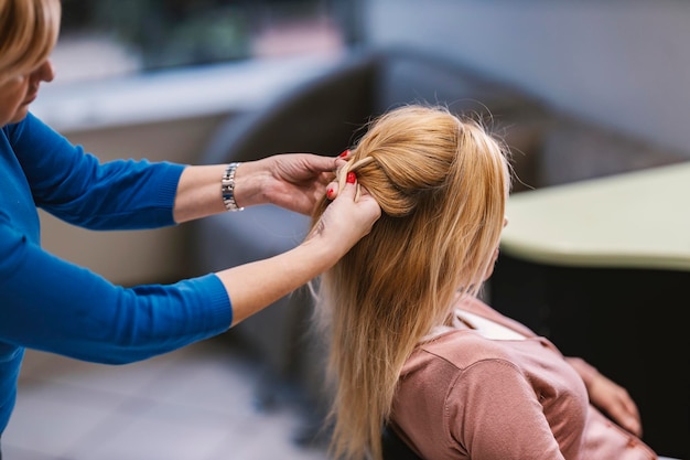 Uma cabeleireira está fazendo uma trança no cabelo de uma cliente em um salão