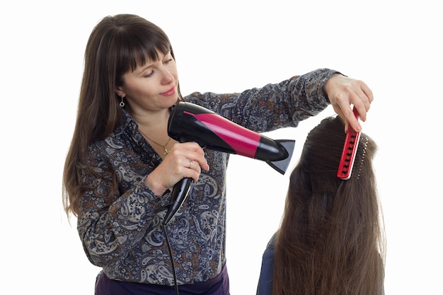 uma cabeleireira penteando o cabelo e secando uma garotinha isolada no fundo branco