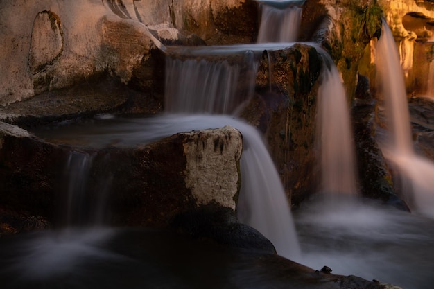 Uma cachoeira à noite com o pôr do sol atrás dela.