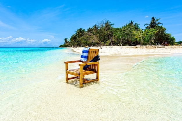 Uma cadeira de madeira em pé no Oceano Índico com uma concha de toalha e nadadeiras
