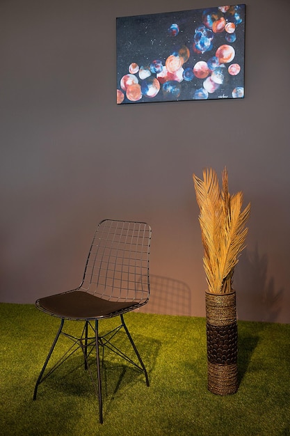 Uma cadeira e uma planta estão sobre um tapete verde com a imagem de uma lua na parede.