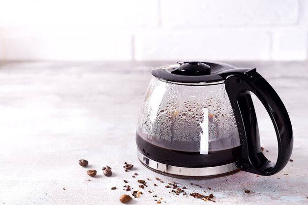 Uma cafeteira cheia com grãos de café contra um fundo cinza de pedra