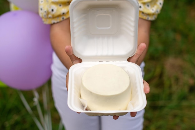 Uma caixa branca aberta com um bolo bento creme nas mãos de uma pessoa