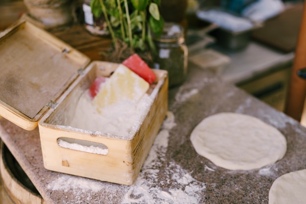 Uma caixa de farinha e massa redonda de pizza sobre a mesa