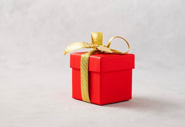 Uma caixa de presente vermelha com uma fita de ouro sobre um fundo cinza O conceito de fotografia de férias Surpresa para o casamento de aniversário do Dia dos Namorados