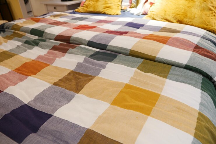 Foto uma cama com um cobertor colorido e travesseiros em tons de laranja roxo e amarelo