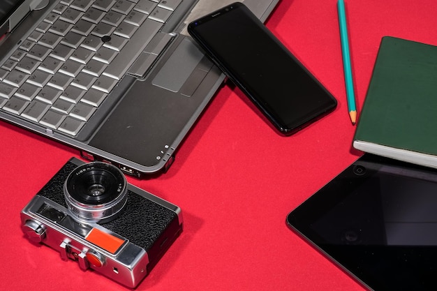 Uma câmera de laptop e celular em uma mesa vermelha Copiar espaço
