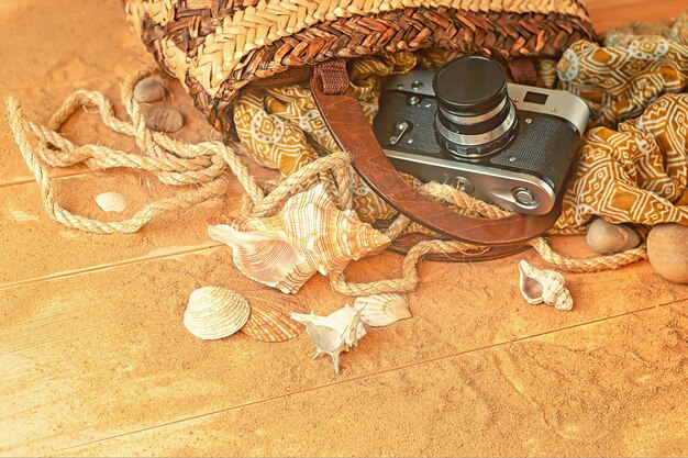 Uma câmera está em uma cesta com conchas na areia