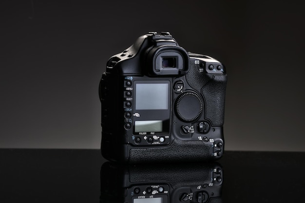 Uma câmera SLR profissional preta senta-se em uma mesa de vidro com uma visão traseira de reflexão