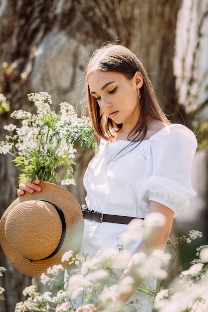 Uma caminhada de uma menina alegre com um buquê de margaridas em um parque de verão 3565