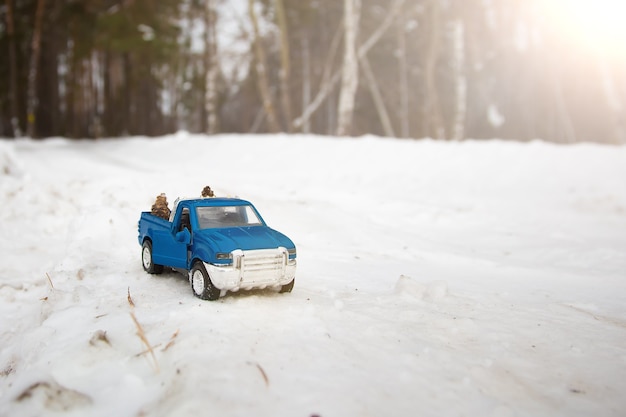 Uma caminhonete azul de brinquedo em uma floresta de inverno com as portas abertas na estrada