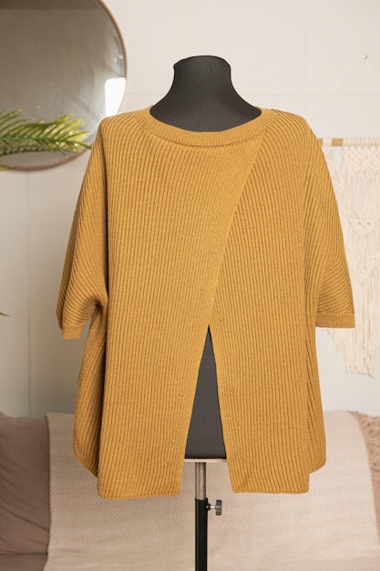 Uma camisola de tricô de mulheres de cor mostarda em um manequim de alfaiate