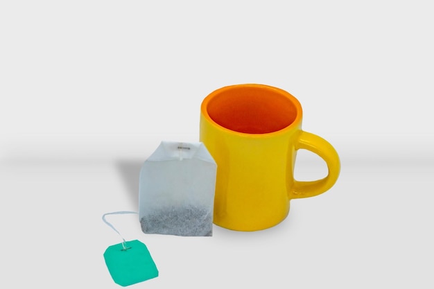 uma caneca amarela com uma alça verde e um saco de chá nela