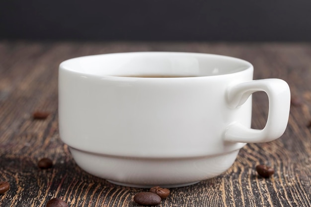 Uma caneca branca com uma bebida preta e grãos de café