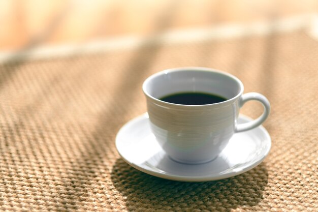 Uma caneca branca de café quente no chão de carpete