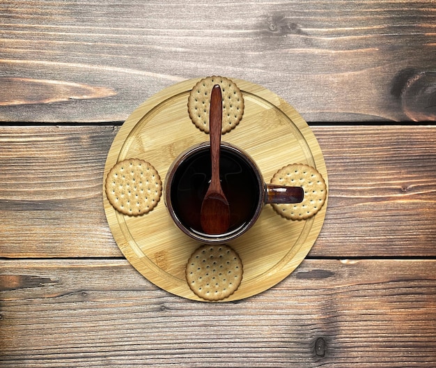 Uma caneca de bebida com uma colher de pau biscoitos em uma bandeja de madeira Vista superior plana