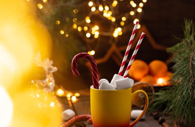 Uma caneca de cacau com marshmallows de que saem palhas, um caramelo em bastão