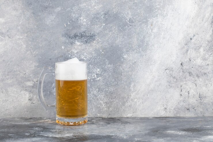 Foto uma caneca de cerveja de vidro com espuma colocada sobre uma superfície de pedra.