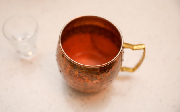 Uma caneca de cobre com um copo de cerveja ao lado