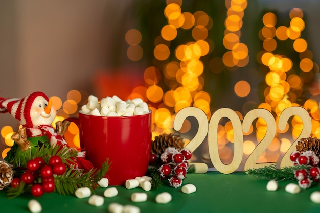 Uma caneca vermelha de Natal com cacau e marshmallows ao lado de um boneco de neve Composição com café e 2022