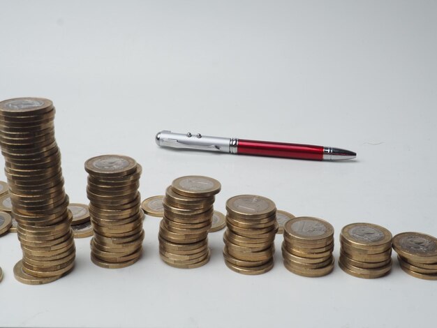 Uma caneta está ao lado de uma pilha de moedas com uma que diz 'pen' nela
