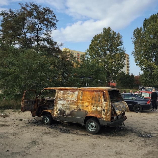 Foto uma carrinha abandonada perto de árvores.