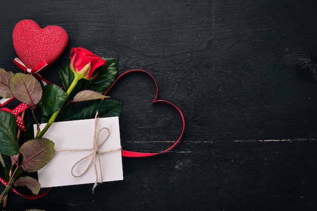 Uma carta para um ente querido. Um envelope, uma rosa, um presente. Em um fundo de madeira. Vista do topo. Espaço livre para o seu texto.