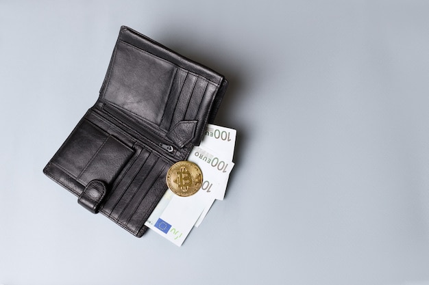 Uma carteira preta com bitcoin de ouro e euro em um fundo cinza. criptomoeda e câmbio eletrônico