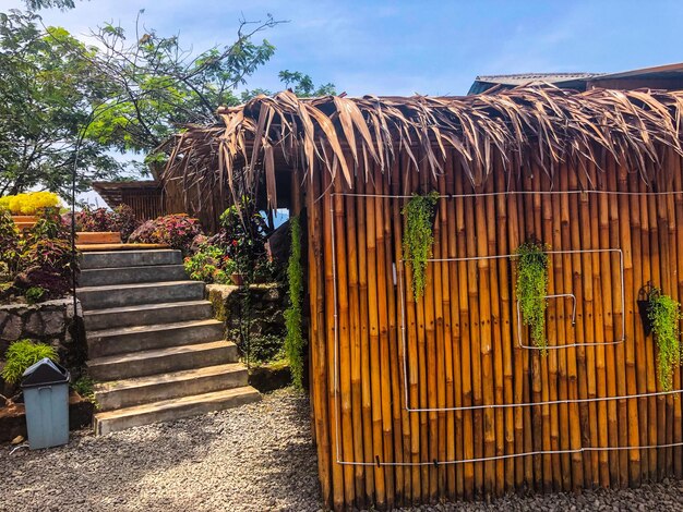 Uma casa com telhado de bambu e escadas que levam à casa.