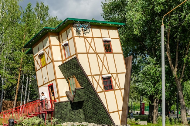 Uma casa com telhado invertido está em um parque.