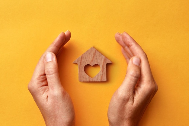 Uma casa de madeira nas mãos de um homem. Um símbolo de proteção e cuidado para o lar e a família