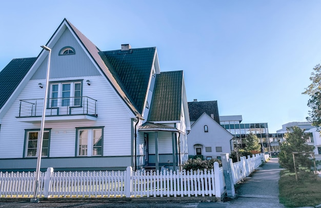 Uma casa particular de dois andares com telhado triangular e uma área perto da casa contra um céu azul