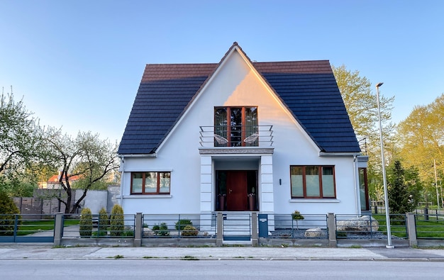 Uma casa particular de dois andares com telhado triangular e uma área perto da casa contra um céu azul