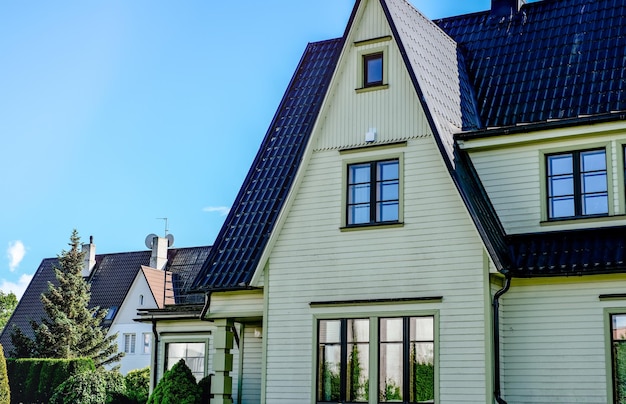 Uma casa particular de dois andares com telhado triangular e uma área perto da casa contra um céu azul