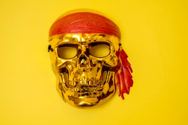 Uma caveira dourada com uma faixa vermelha em um fundo amarelo Pirataria de Halloween Jolly Roger O sinal dos piratas Crimes de roubo Ladrões do mar Banner Espaço para texto Copiar espaço