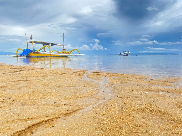 Uma cena de praia com um barco na água e o céu nublado.