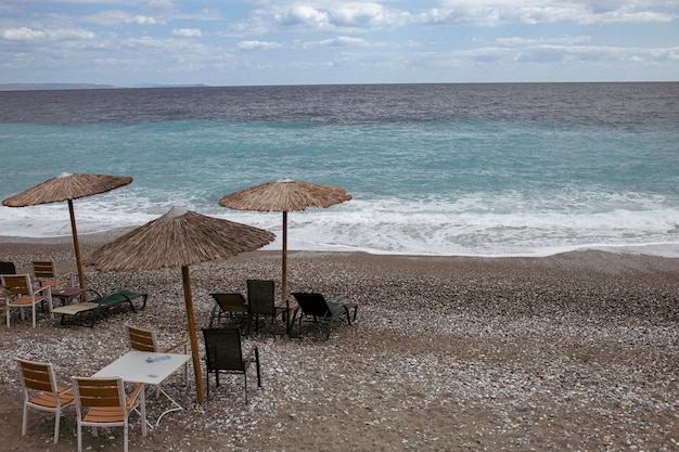Foto uma cena de praia tranquila com cadeira de guarda-sol e guarda-chuva de palha