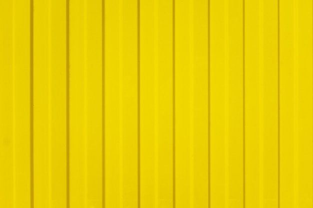 Uma cerca ondulada de folhas de metal amarelo com parafuso. textura de cerca de metal